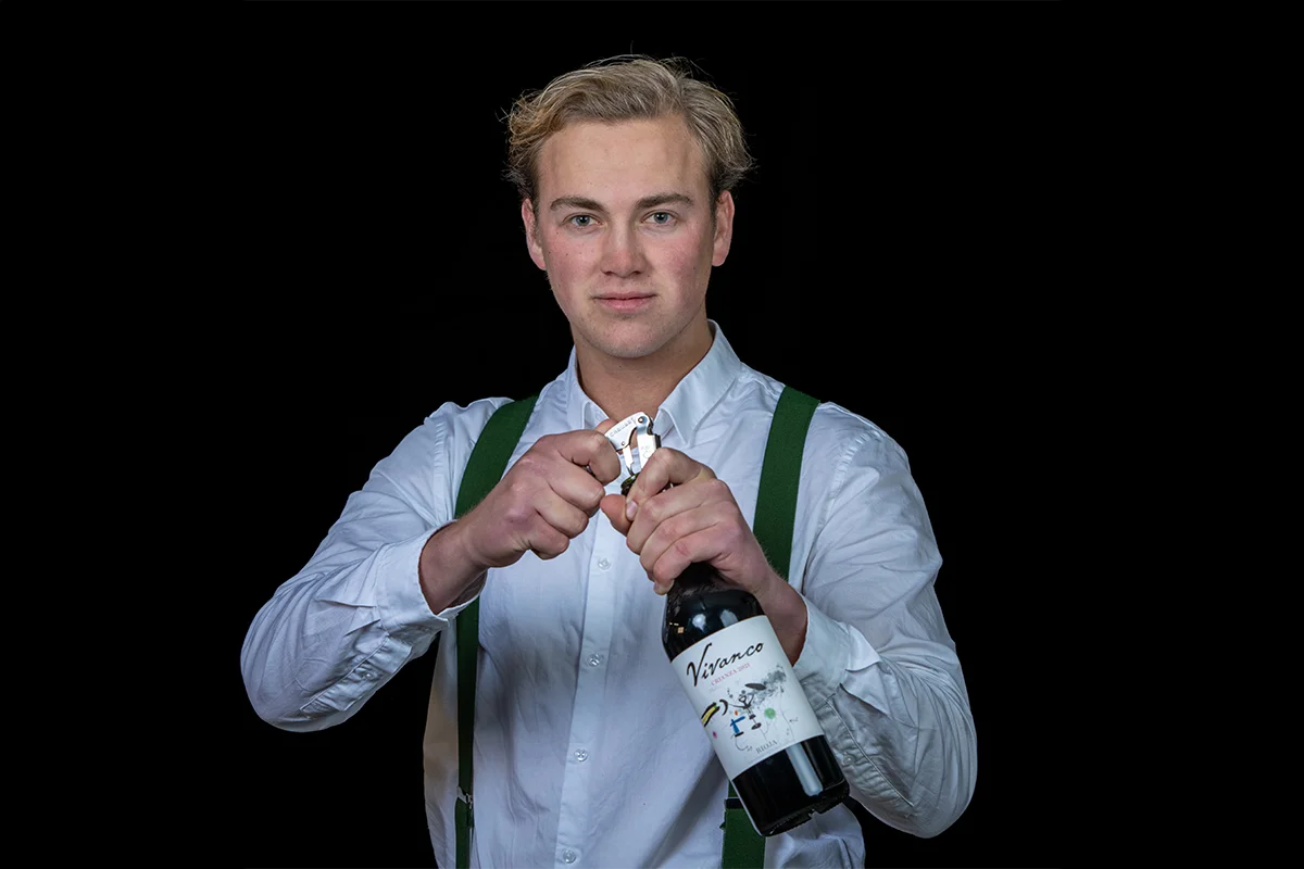 Bedieningsmedewerker vacature bij Restaurant WOODS Bedieningsmedewerker van Restaurant WOODS opent een fles wijn voor gasten