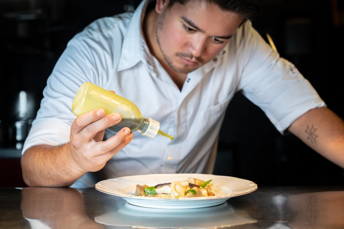 Chef de Partie vacature bij Restaurant WOODS Chef de Partie van Restaurant WOODS werkt een gerecht zorgvuldig af in de open keuken