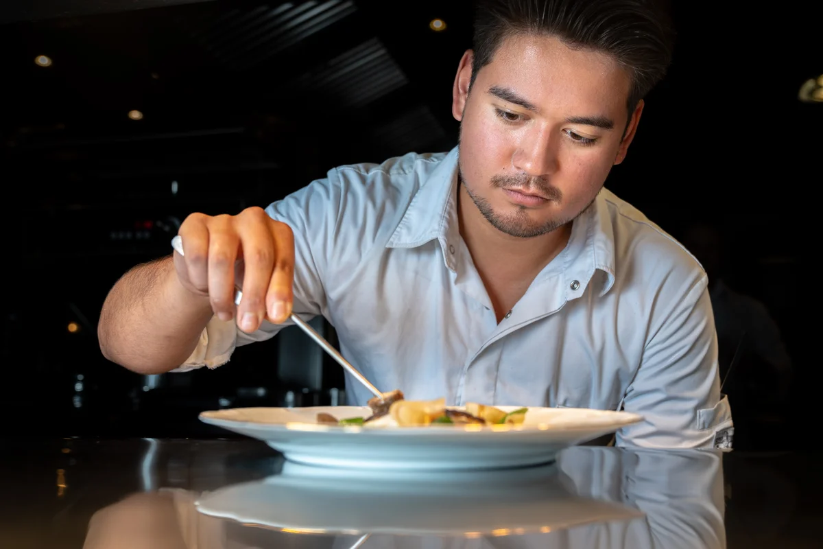 Chef de Partie aan het werk bij Restaurant WOODS Chef de Partie van Restaurant WOODS werkt een gerecht nauwkeurig af in de keuken