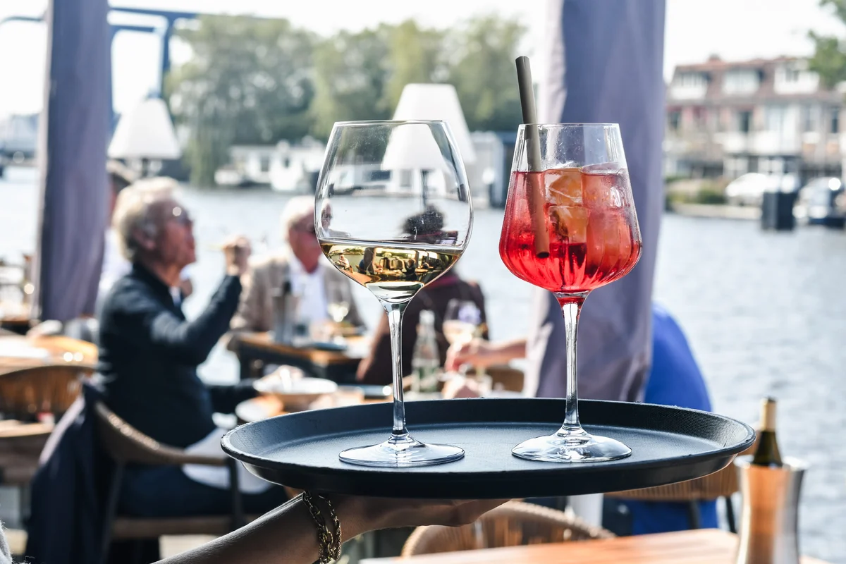 Chef de Rang bij Restaurant WOODS Bedieningsmedewerker serveert wijn en cocktails op het terras van Restaurant WOODS aan de Oude Rijn